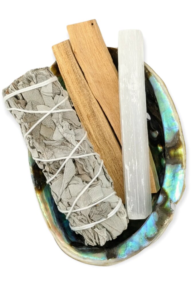 White sage bundle, palo santo sticks and a selenite wand in an abalone shell